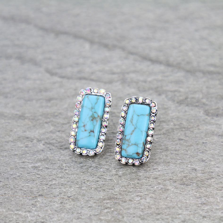 Pair of turquoise earrings with silver accents on a gray background